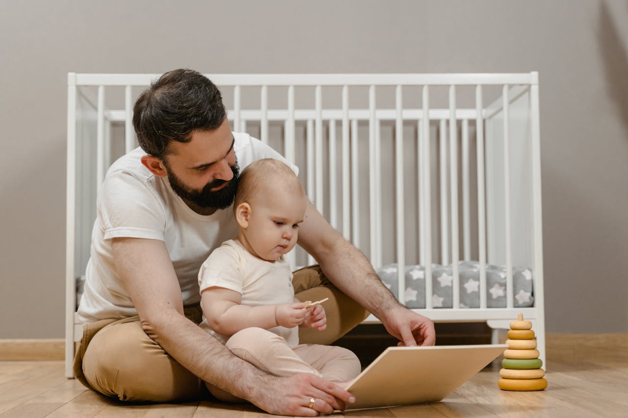 Dad and baby bonding indoors with toys and book, capturing the warmth of parenthood.